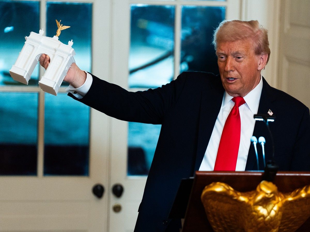 Donald Trump holding up a model of an arch