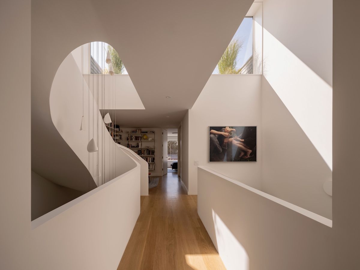Sunlight beams into the home from the uppermost windows, while the shapely staircase beguiles.