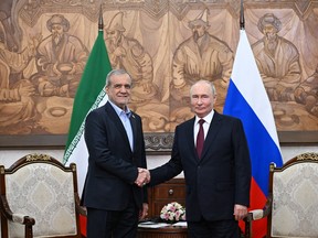Russia's President Vladimir Putin (right) and Iran's President Masoud Pezeshkian (left) shake hands.