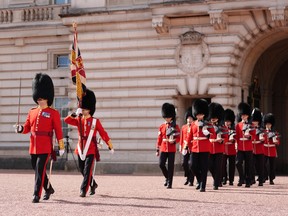 Buckingham Palace guards march in a line in the forecourt.