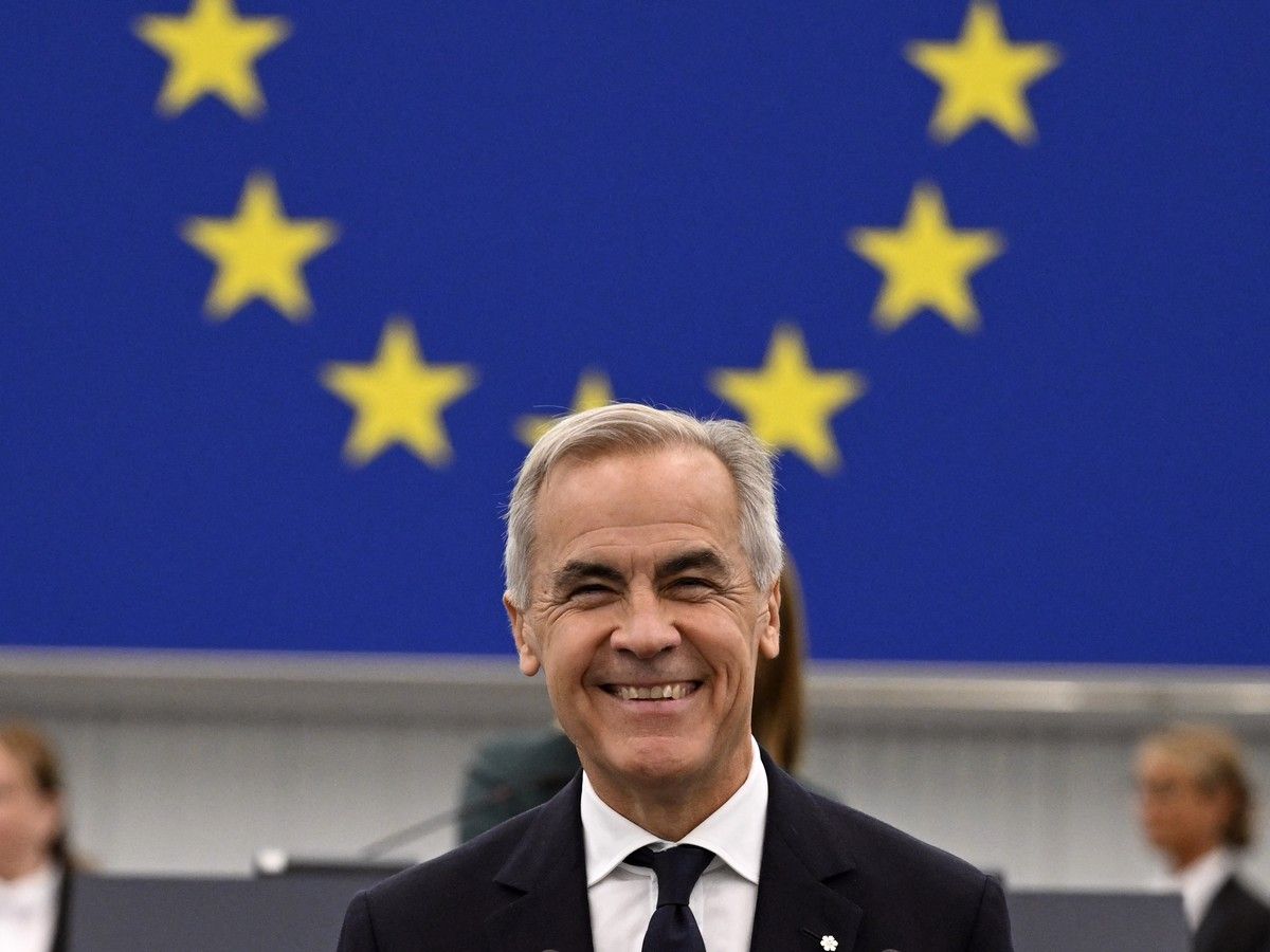 Mark Carney smiles in front of a European flag.