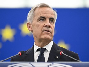Mark Carney speaking into microphones with a European flag in the background