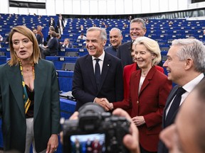 Mark Carney (centre) smiles while shaking hands with Ursula von der Leyen (right). Roberta Metsola stands to their left.