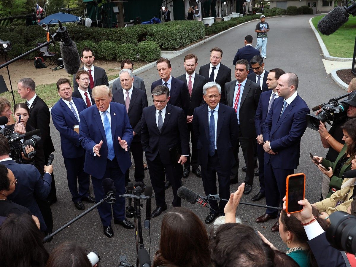 Trump stands with tech CEOs in front of members of the press holding phones and microphones.