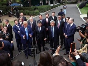 Trump stands with tech CEOs in front of members of the press holding phones and microphones.