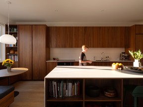 The rich walnut kitchen crafted by Harvest House features integrated pulls, a Mutina-tile backsplash and slim Corian countertops.