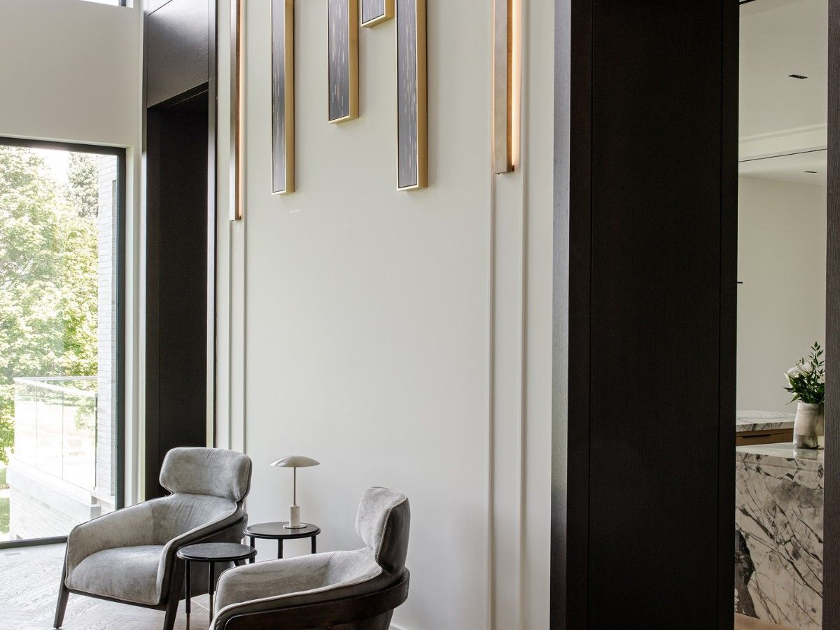 Custom art by Tony Koukos hangs between a pair of slim sconces, which are in turn set between doorways to the kitchen and breakfast area. It’s a study in height and symmetry, and contrasts with the sprawling landscape beyond the adjoining windows.