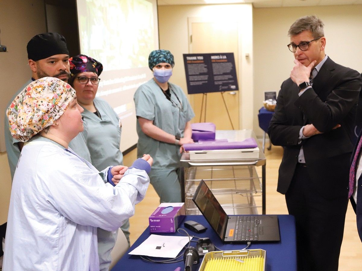 Man in suit watches as hospital nurse describes some equipment