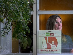 A woman sits in a window with a Block Parent sign