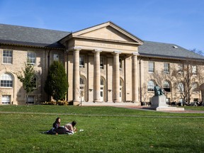 Cornell University students sit outside a campus building on an early fall day