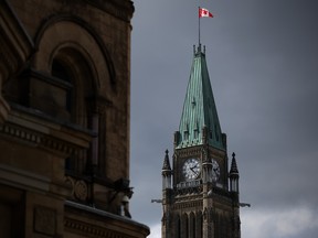 Peace Tower on Parliament Hill with a Candian flag on top in front of a cloudy sky.