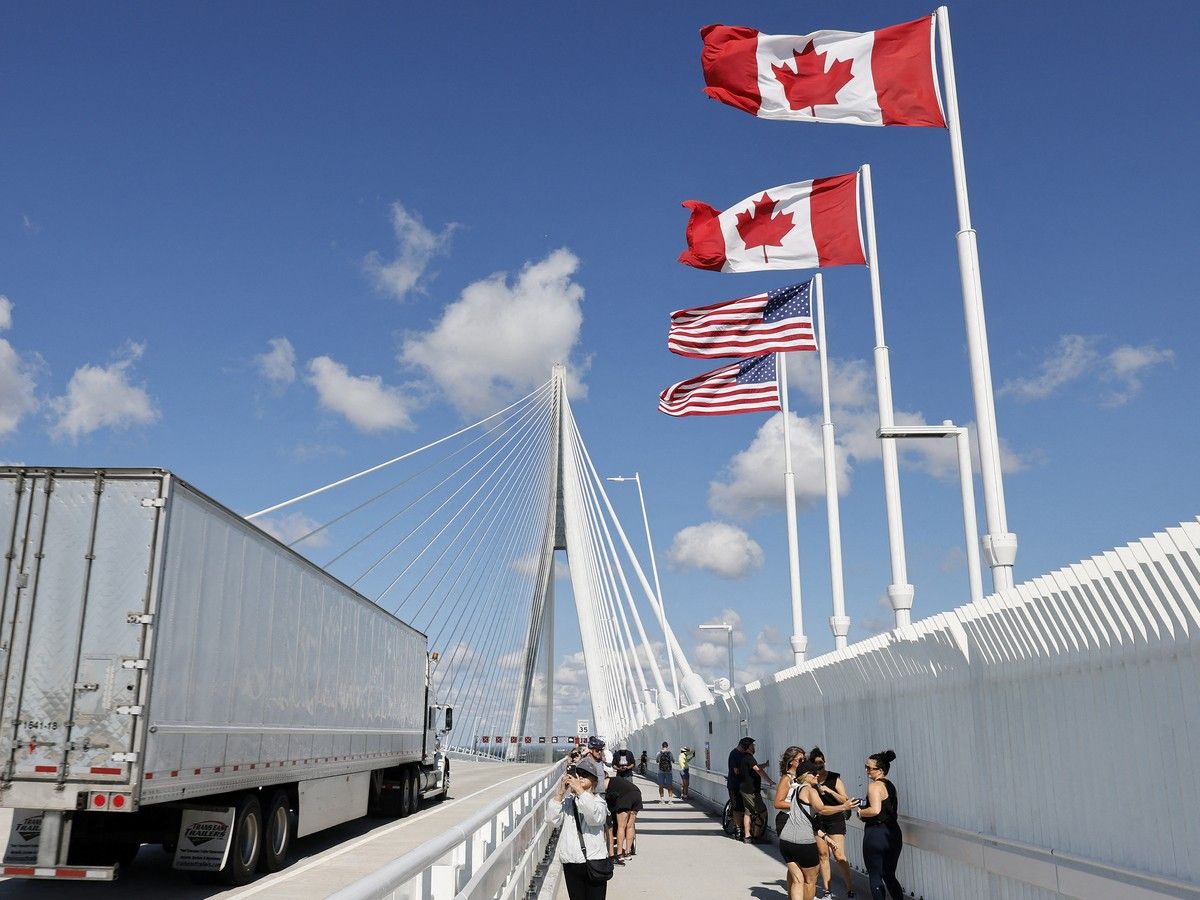 a truck passes by as pedestrians stop on a bridge