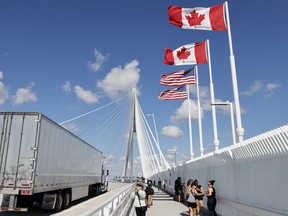 a truck passes by as pedestrians stop on a bridge