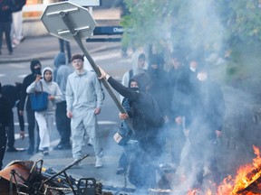 A protestor throws a stop sign into a fire