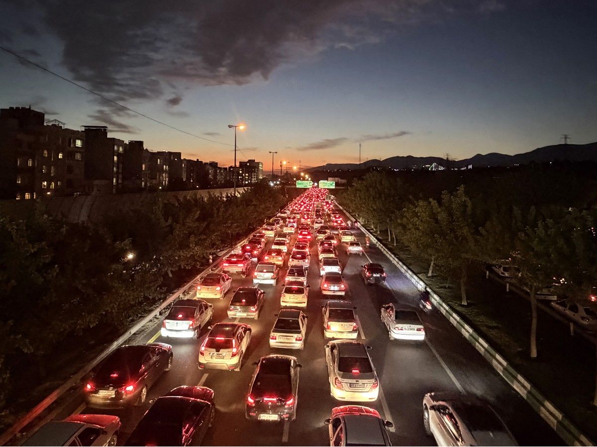 Vehicles drive along a busy road during the evening