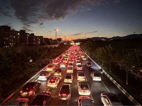 Vehicles drive along a busy road during the evening