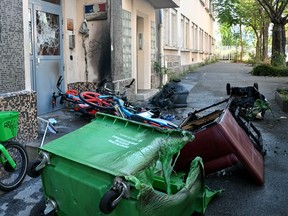 Burned garbage bins, furniture and bicycles in front of the damaged entrance