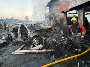 Firefighter next to a burned out car