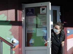 A security person wearing a face mask looks out from a door