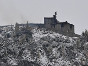 Smoke outside a building on top of a snowy hill under a grey sky.
