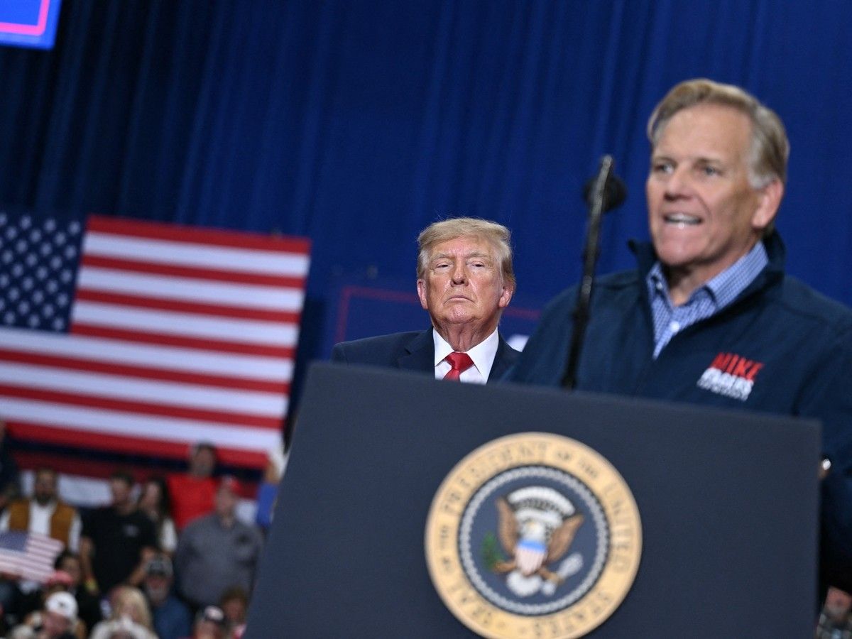 Donald Trump looks on as Mike Rogers speaks at a campaign rally.