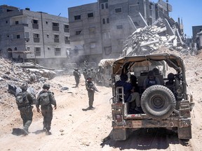 Soldiers walk among rubble.