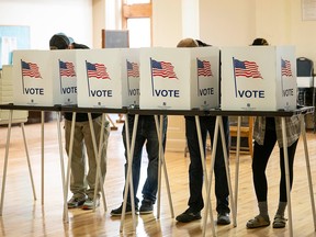 People standing behind ballot boxes.