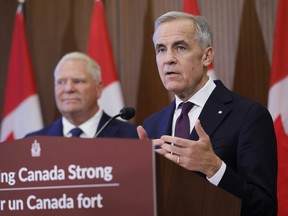 Mark Canrey speaks from behind a lectern as Doug Ford stands in the background.