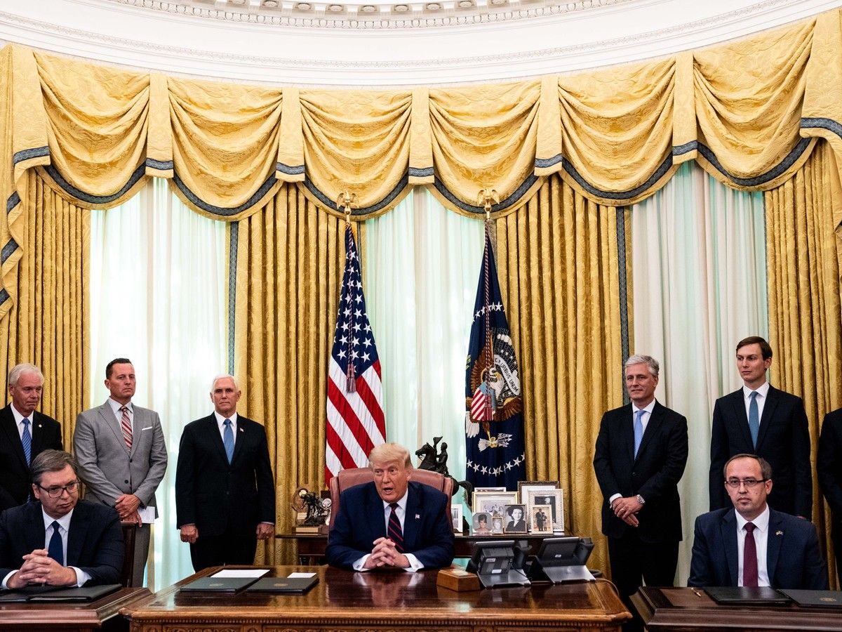 Donald Trump sits at a table in the Oval Office with President of Serbia Aleksandar Vucic (L) and the Prime Minister of Kosovo Avdullah Hoti (R) sat beside him.