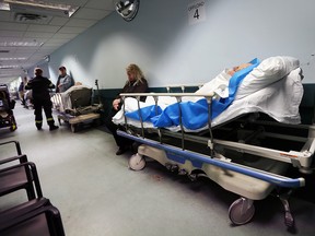 Hospital patients on beds in a hallway.