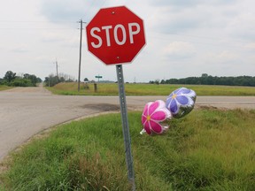 Two memorial flower balloons twirl in the wind around the stop sign at the intersection of Nairn Road and McEwan Drive, the location of a fatal two-vehicle collision on Monday. A seven-year-old girl died of her injuries and her mother is in hospital in critical, but stable condition. (SHANNON COULTER, The London Free Press)