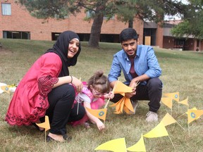 Haleema and Osama Chaudhry plant flags with young cancer patient Sophie O'Brien in front of St. Lawrence Secondary School on Thursday September 20, 2018 in Cornwall, Ont. Alan S. Hale/Cornwall Standard-Freeholder/Postmedia Network