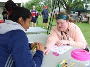 Polly Singh creates a henna tattoo for Shelby Emery during the 2018 Art in the Park, held in Mike Weir Park in Sarnia's Bright's Grove.
