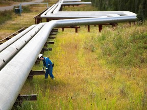 A man works next to pipelines at Cenovus Energy's Foster Creek plant, on the Cold Lake Air Weapons Range.