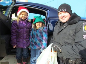 The eighth annual Cops for Cans food drive is happening Saturday in Sarnia from 10 a.m. to 3 p.m. In this file photo,
sisters, from left, Alyson Laird and Katelyn Laird, drop off a donation with Const. Jim McCabe at a previous Cops for Cans. The food donations from the public are passed along to the Inn of the Good Shepherd.