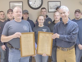 Exeter fire station assistant district chief Danny Smith, left, and former Exeter resident Tom Creech, right, hold two historical plaques that Creech recently donated to the Exeter station. The plaques, bought by Creech at an auction in the 1970s, detail the bylaws and rules of Exeter's fire stations in the early 1900s.