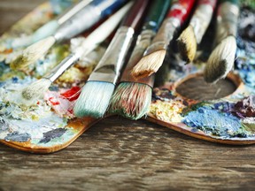 Artist paint brushes and palette on wooden background