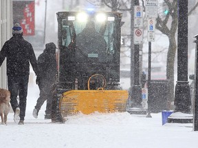 Pedestrians get out of the way of a sidewalk plow on Princess Street during a snowstorm in Kingston on Tuesday, Feb. 12, 2019.