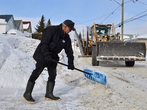 In this file photo, Fern Robillard clears the foot of his driveway on Leslie Street, while a city plow pushes chunks of ice and snow aside.