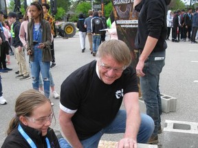 Henry Veenzliet of Veenzliet and Sons Masonry gives Katrina-Ann Thompson, 14, a student at Agnes Hodge School, a hand spreading mortar on a pillar created by students on Wednesday at Epic Jobs, an event to promote skilled trades. Michelle Ruby