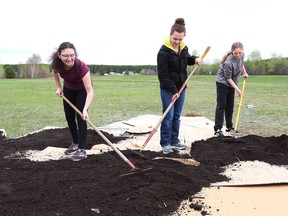 Ecole secondaire Hanmer students Stefany Lemieux, 17, left, Sarah Poulin, 15, and Abby Lafave, 14, spread soil over cardboard for an edible forest garden at the school in Hanmer, Ont. on Friday May 24, 2019. One is now planned for Alban.