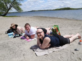 Amie Thain, left, Tianna Mageran and Julian Semczyszyn catch some rays at the main beach at Bell Park in this file photo. Sudbury remains under a heat warning.