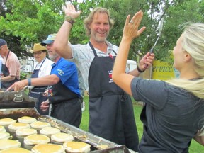 In this file photo, Mark and Melissa Lumley high five after another successful batch of pancakes during the Rotary Club of Sarnia Mackinac Race breakfast. This year's breakfast has been cancelled due to the pandemic, but the race is scheduled to go ahead Saturday.