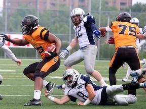 Sudbury Spartans Victor Paajanen (20) and Andrew St. Amour (8) attempt to tackle Ottawa Sooners ball-carrier Nyjill Wilson (85) while the Spartans' Erik Conrad (32) rushes to help during Northern Football Conference quarter-final action at James Jerome Sports Complex in Sudbury, Ontario on Saturday, July 27, 2019.