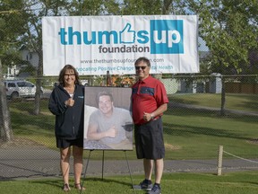 Kim and Kim Titus pose with a photo of their late son, Braden Titus, at the fourth annual Thumbs Up Foundation Golf Tournament Wednesday, Aug. 21, 2019. The tournament helps to raise funds for local mental health initiatives.