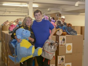 Nancy McPhee and her son Stephen, the leaders of Stephen's Backpacks Society, pose in the Calgary warehouse on Sunday, Aug. 25 as hundreds of backpacks are distributed to schools and children in need. This year, the society will be giving out approximately 2,000 backpacks and 150 teacher kits.