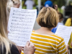 A mass choir volunteer reads the sheet music for the song 'Happy' by Pharrell Williams.