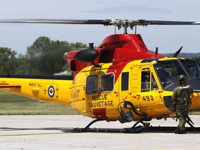 A crew member stands next to a CH-146 Griffon helicopter at Canadian Forces Base Trenton, Ont. Thursday, June 16, 2016.