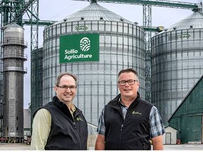 Sollio Agriculture's grain general manager for Ontario, Paul Hazzard (left), and Sollio's originations supervisor Andrew Woodbridge stand in front of the company's new sign that was recently erected on the Becher grain elevator on Lambton Line. (Submitted photo)