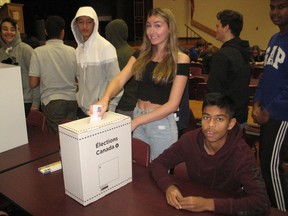 Grade 10 student Isabel McDonell casts a ballot at CCVS, with voting day assistant and Conservative Party campaign manager Tharuyan Nallaiah seated. Photo on Friday, October 18, 2019, in Cornwall, Ont. Todd Hambleton/Cornwall Standard-Freeholder/Postmedia Network